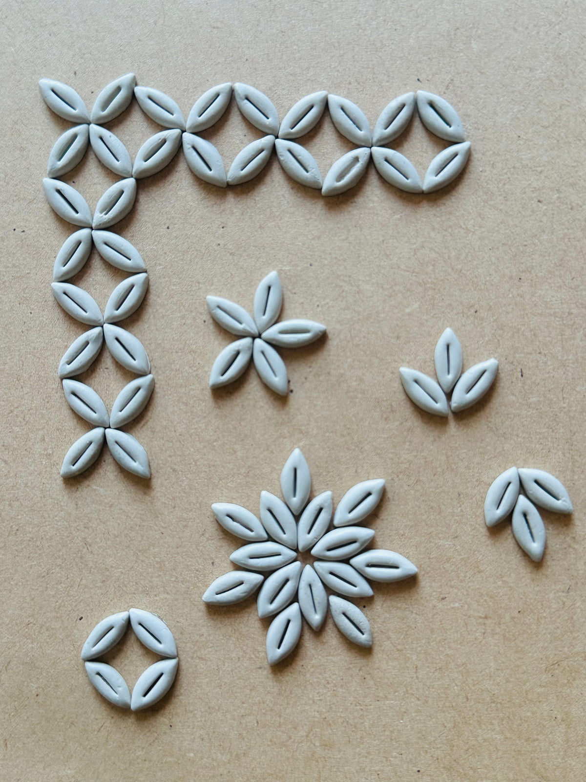 Leaf bead shape white clay pieces arranged in floral and border patterns, ideal for Lippan art, mud mirror work, and DIY craft decoration.