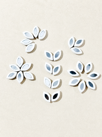 Leaf petal shape white clay beads with center mirrors arranged in floral patterns for Lippan art and DIY craft decoration.